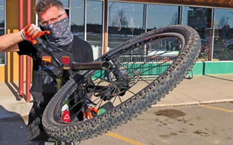 Pat White wears a mask as he wrestles with a bicycle at his Grand Forks business, The Ski and Bike Shop, which has felt the effects of a nationwide bike shortage due at least in part to the COVID-19 pandemic. Photo submitted