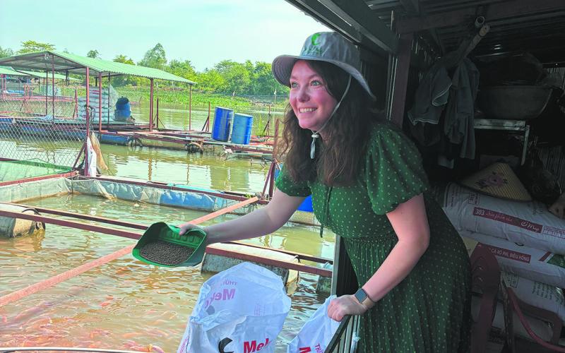 Billie Lentz of Perth tried her hand feeding fish at an aquaculture operation. ND Soybean Council photo