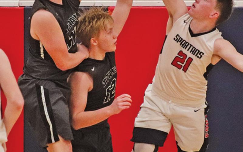 Alex Swanson and Caleb Kartes attempt to block a shot put up by Spartan Blake Jacobsen. VNV Photo by Lesa Van Camp