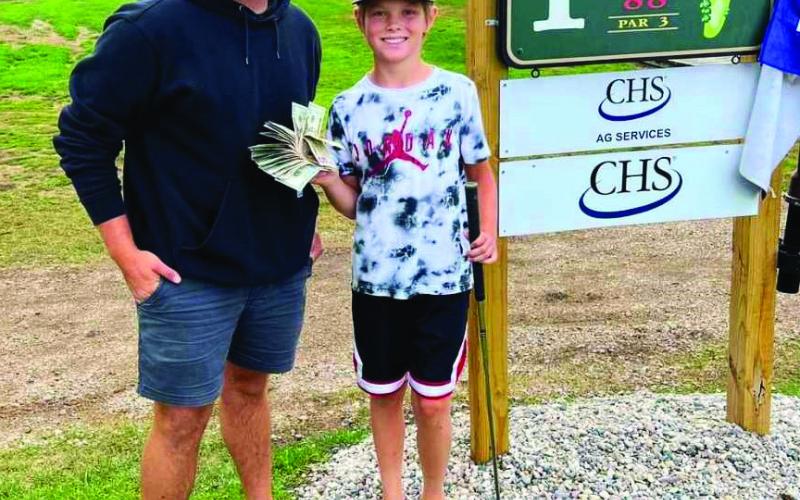 Tyber Pokrzywinski and Asher McFarland pose at hole #1 with Asher’s winnings. Photo by Genafay Pokrzywinski.