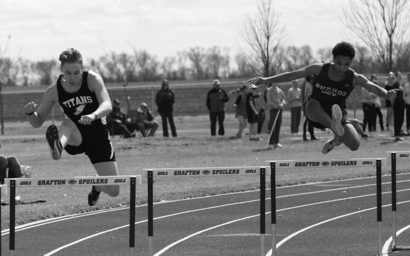 Gavin Ryan, left, clears the hurdle the same time as a runner from Hillsboro. Miller finished with a personal best in the 300 meter hurdles.