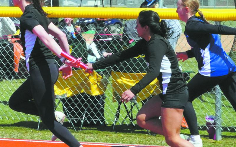 Jocelyn Vold and Mabelline Blanco compete in the 4x100 relay finishing third. Photo by Larry Stokke.
