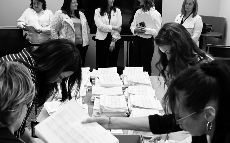 Members of the sponsoring committee for a proposed ballot measure to make public school meals free watch as staff with the North Dakota Secretary of State’s Office count petition signatures on April 9, 2026. (Photo by Mary Steurer/North Dakota Monitor)
