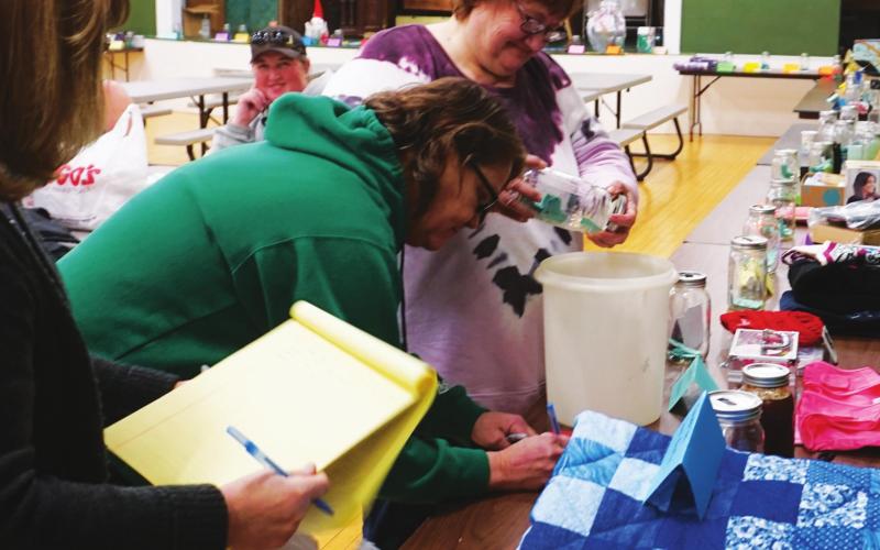 Tammy Puppe, Polly Pokrzywinski, and Sandi Bratlie draw the winners names at the silent auction Sunday evening. VNV photo by Lyle Van Camp