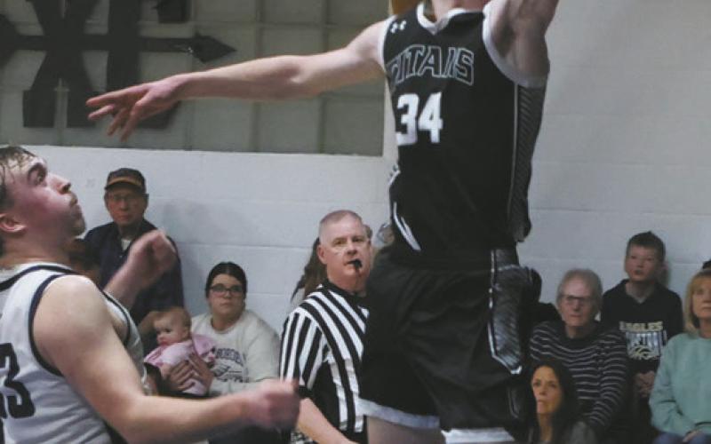 Extending for the basket, DVE senior Jack Langerud leaps past North Border defender Kade Schafer for the shot. Photo by Jamie Rarick
