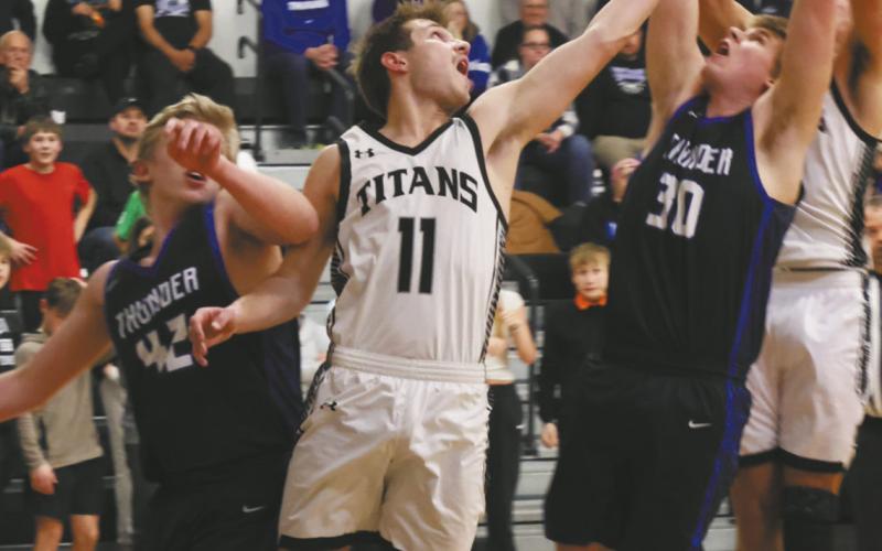 DVE senior Isaac Feltman extends to go for the rebound past Hatton-Northwood players Owen Poppema and Trayson Monkeby. Photo by Jamie Rarick