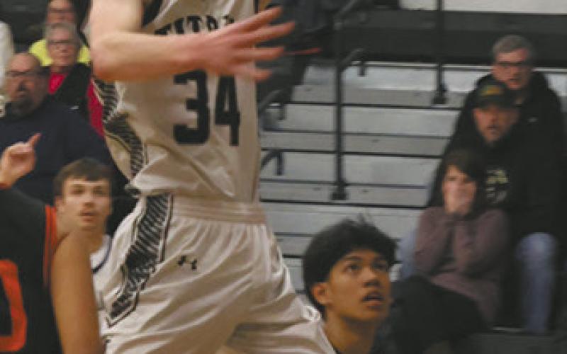 Soaring through the air, DVE senior Jack Langerud extends for the basket against Warwick Warrior defenders Feb. 20 on his home court. Photo by Jamie Rarick