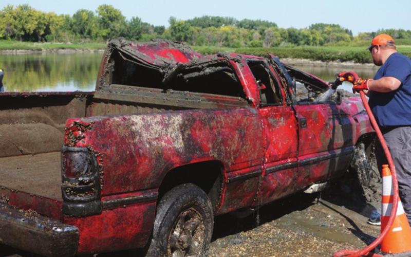 Drayton Fire Chief Jordan Grundstrom washs some of the river mud off of the pickup after it was recovered. VNV Photo by Lyle Van Camp