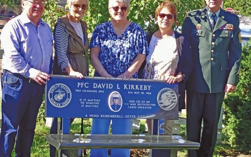 Standing behind the bench placed in honor of David Kirkeby are some of his high school classmates with Drayton Mayor Chip Olson following the flag raising last Wednesday morning. Pictured left to right: Andy Dunklee, Cheryl Gjevre, Mary Lou Kirkeby, Pam Scharmer, and Mayor Chip Olson. Photo submitted by Kirkeby family