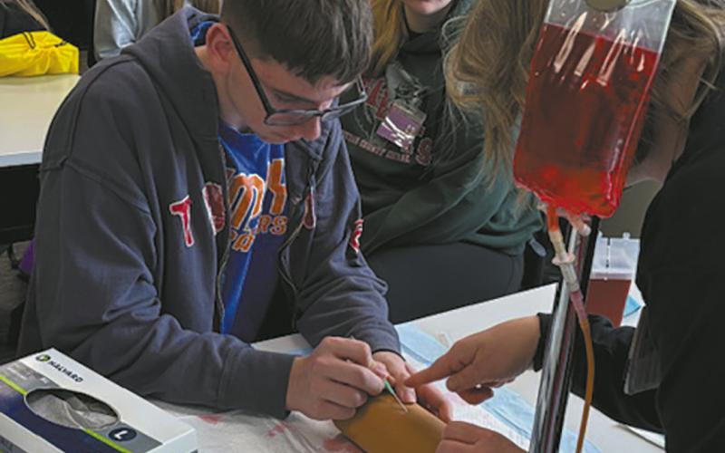 Jonah Rarick carefully inserts an IV with guidance from a hospital nurse. Submitted photo.
