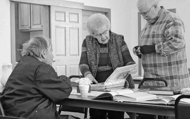 Pictured left to right are Tim Bloomquist, Marlys Nelson, and Steve Marten looking through the book of memories and pictures that Marlys compiled for the project. VNV Photo by Lesa Van Camp