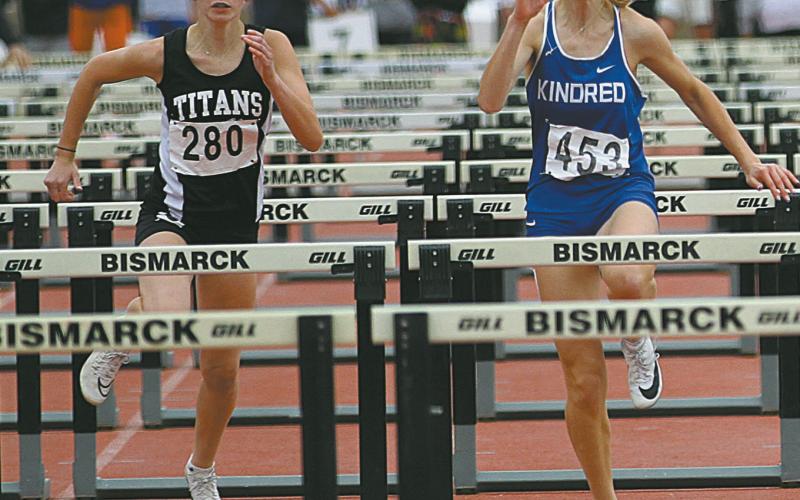 Freshman Jocelyn Vold, left, races alongside Kindred’s Ashley Haas during the preliminaries in the Class B Girls’ 100 meter Hurdles Friday. Vold qualified for the finals and finished in Seventh Place overall with a time of :16.03. Photo by Mike Alan Steinfeldt