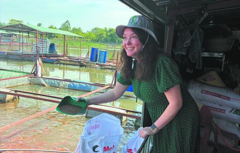 Billie Lentz of Perth tried her hand feeding fish at an aquaculture operation. ND Soybean Council photo