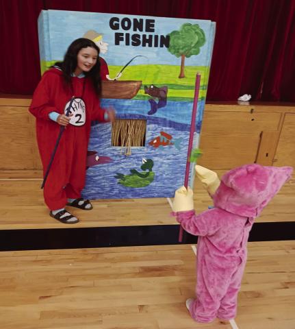 Tess Sehrt helps Elsie Littlejohn play a ‘fishing’ game on Saturday.
