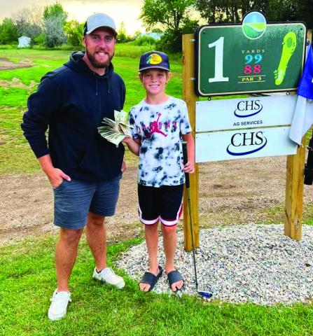 Tyber Pokrzywinski and Asher McFarland pose at hole #1 with Asher’s winnings. Photo by Genafay Pokrzywinski.