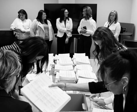 Members of the sponsoring committee for a proposed ballot measure to make public school meals free watch as staff with the North Dakota Secretary of State’s Office count petition signatures on April 9, 2026. (Photo by Mary Steurer/North Dakota Monitor)