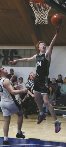 Extending for the basket, DVE senior Jack Langerud leaps past North Border defender Kade Schafer for the shot. Photo by Jamie Rarick