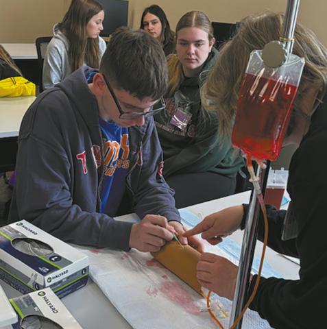Jonah Rarick carefully inserts an IV with guidance from a hospital nurse. Submitted photo.
