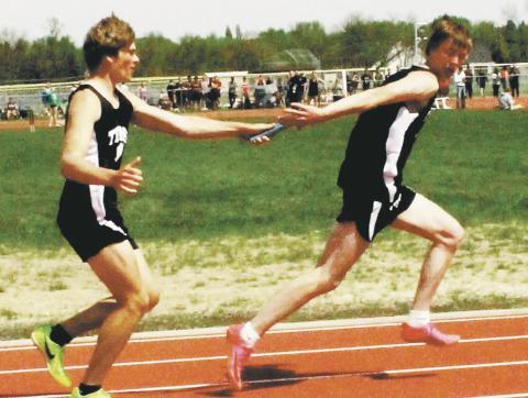 Sam Kittelson hands off to Jack Langerud in the boys 4x100 relay. The relay team, also including Mason Pollestad and Carter Johnson, finished third, qualifying for state. Photo by Jamie Rarick