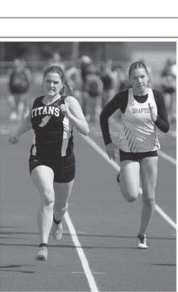 Greta Burrell, left, took first in her heat in the 100 meter dash. At right is Grafton Junior Molly Bjorneby.