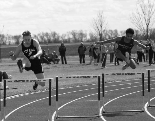 Gavin Ryan, left, clears the hurdle the same time as a runner from Hillsboro. Miller finished with a personal best in the 300 meter hurdles.