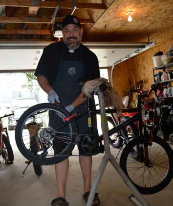 Rev. Lefor tunes up one of the eight bikes to be given away as door prizes at the Nepomuk Narly cycling race to be held June 22 in Pisek. Photo by Todd Morgan, Walsh County Record.