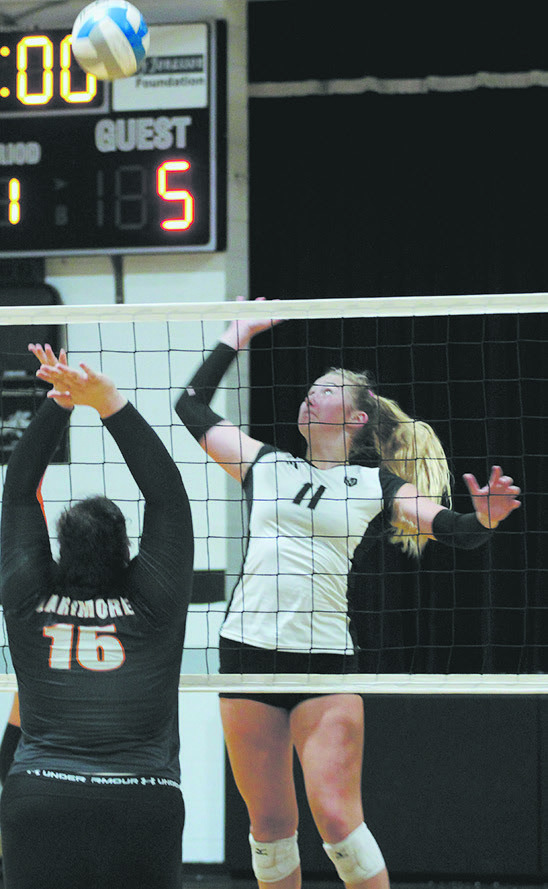 Titans sophomore Reegan Aasand jumps for the spike while Larimore defender Zoey Stone rises to attempt a block. Photo by Jamie Rarick