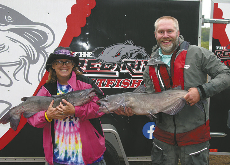 First-place winners May Thompson of East Grand Forks and Jayson Ackerson of West Fargo show off two of their Day 2 catches, weighing 18.83 and 16.41 pounds. The pair brought 41.31 pounds to the scales on Day 2 and finished the Drayton Catfish Capital Tournament with a winning two-day total of 76.68 pounds. Photo by Rob Boll