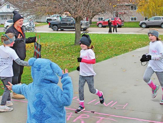 At the finish line to cheer on Natalie Helm and Lana Kalka as they finished their 5K run were Katie Dahl, Brynlee Christenson, and in costume Caleb Rarick. Photo submitted by Jamie Rarick