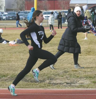 Serving as both a coach and a mom, Coach Jodi Fedje moves along the sidelines, encouraging Rosalyn Fedje during the girls 400m. Fedje won second place in the race. Photo by Jamie Rarick