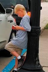 Caleb Rarick reads his bible while leaning against a lightpost. Photo by Cindy Johnson.