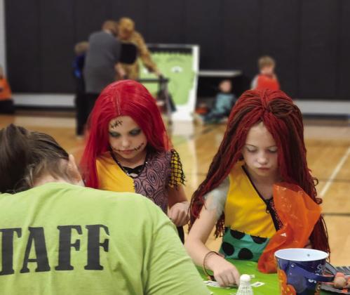 Nora Patterson and Sophie Woinarowicz wait at a table amidst all the Halloween activities taking place.