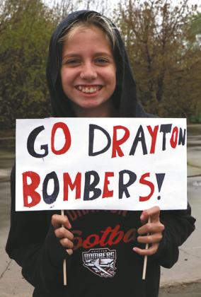 Ruthie Rarick holds up a sign supporting the team as they head for Minot. Photo by Lyle Van Camp