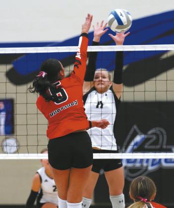 Alyssa Hoyles blocks the ball from Mustangs' junior Mia Villanueva. Photo by Larry Stokke.