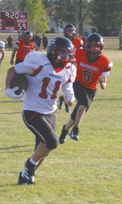 Flanked by Warriors' defenders Valdon Morin and Michael Black, Bomber eighthgrader Keegan Ryan runs the ball in for a touchdown. Photo by Jamie Rarick