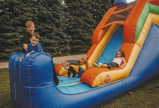 Hunter Gullickson, Emmett Paulson, Ila Hall, and Beckam Evenson enjoy the bounce houses with a toddler.