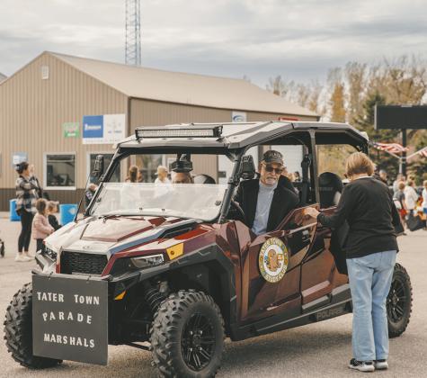 Loren Gullickson driving the ATV for the Parade Grand Marshall's, The Hoople Study Club while refilling Sue Fagerholts treat bag to pass out candy.