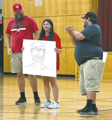 Coach Foster admires Allison Chavez's drawing of him while coach Smith applauds her work. Photo by Lyle Van Camp