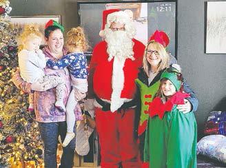 Hadley and Everly with their mother Megan, Chris Van Camp as Santa, Jamie Twamly as an elf, and Daidralynn Manley as a little elf. Photo by Paul Larocque.