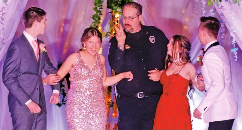 Drayton City Officer Ian Mattice let the boys know that he had his eyes on them and then escorted their dates through the walkway of the Grand March Pictured l to r: Evan Feltman, Rylee Maurstad, Officer Mattice, Jazalyn Rathke, and Hunter Johnson. VNV Photo by Lesa Van Camp