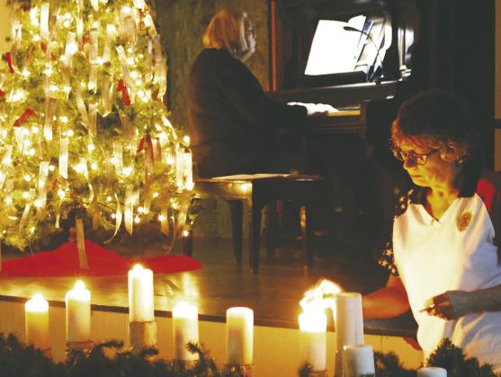 Kristi Scharmer lights the candles while Shirley VanCamp plays in the background. Photo by Lyle Van Camp.