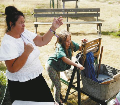 Catherine Betchel (Kari Helgoe) shares about her family while a visitor uses a wringer washer. Photo by Larry Stokke