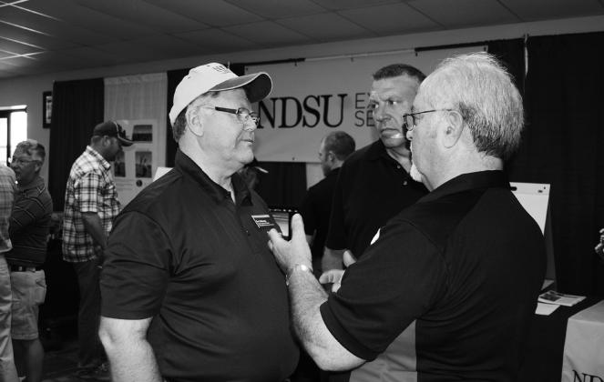 Ken Hellevang, NDSU Extension agricultural engineer (left), talks to visitors at the Big Iron farm show. NDSU photo.