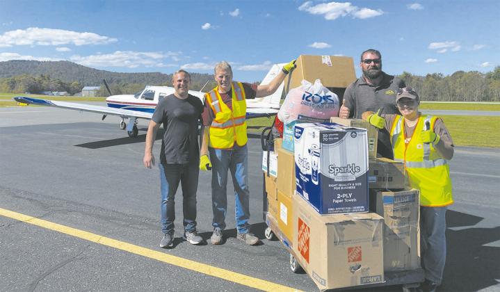 Casey Veil (left, black shirt) and Treven Iverson (right, sunglasses) of Jamestown pose with volunteers and the supplies they flew into a distribution point in Jefferson, N.C. on Oct. 5. Photo contributed by Veil.