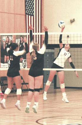 Lined up against Cavalier's Jaylynn Stegman and Katy Jensen, Elizabeth Fedje tips the ball back over the net. Photo by Jamie Rarick