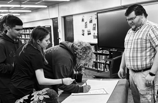 “The newly formed FFA group pictured with their leader, Mr. Riddle” and “Charter members line up to sign their official FFA certificate” Photo by Jackie Dvorak.