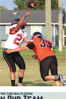 Hunter Johnson gets a pass off before being hit by the Warrior’s TJ Longie. Photo by Lyle Van Camp.