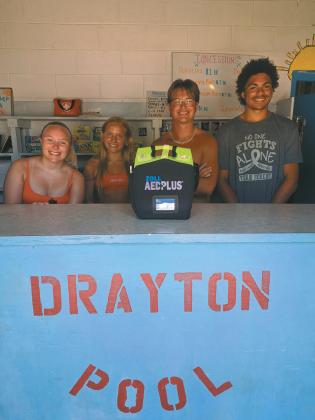 Drayton Pool lifeguards (l to r) Gracie Johnson, Reese Fering, Jonathan Knudson, and Mason Pollestad stand with one of the defibrillators placed at the pool. It’s one of several being placed strategically around Drayton and is a life saving tool for prehospital treatment for cardiac arrest. Photo by Christine Jensen.
