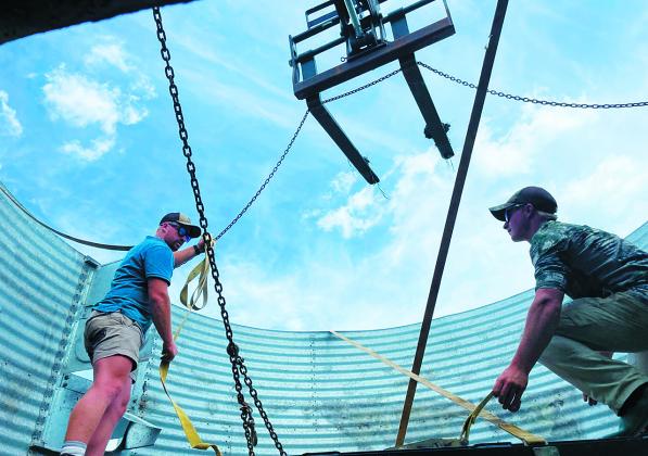 Brothers, Ryan [23, left] and Richard [19, right] Kemp, workers from South Africa on H-2A visas, prepare an old grain bin for transfer to another section of Stephanie Hatzenbuhler’s ranch just west of Mandan. Photo Michael Standaert.