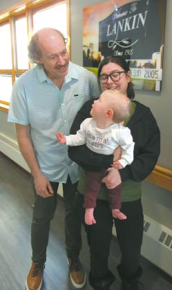 Baby Allara looks back and smiles at Dr. Joel Johnson while being held by her mother, Samantha Kartes. Submitted photo